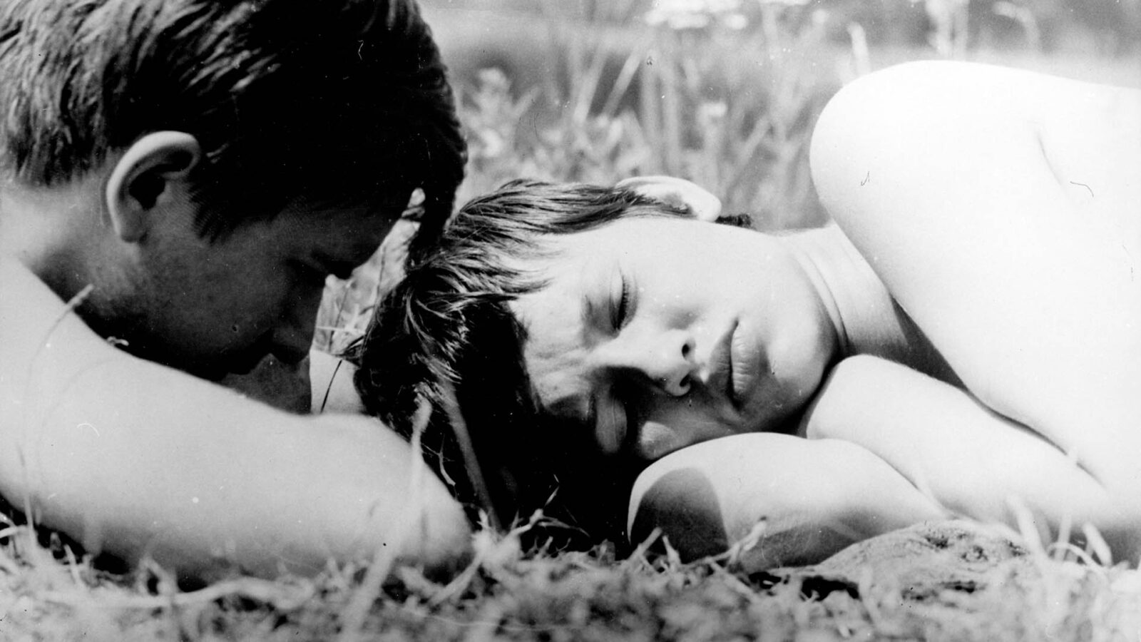 Filmstill aus dem Film "Der schwarze Peter". Ein Mann und eine Frau liegen auf einer Wiese.