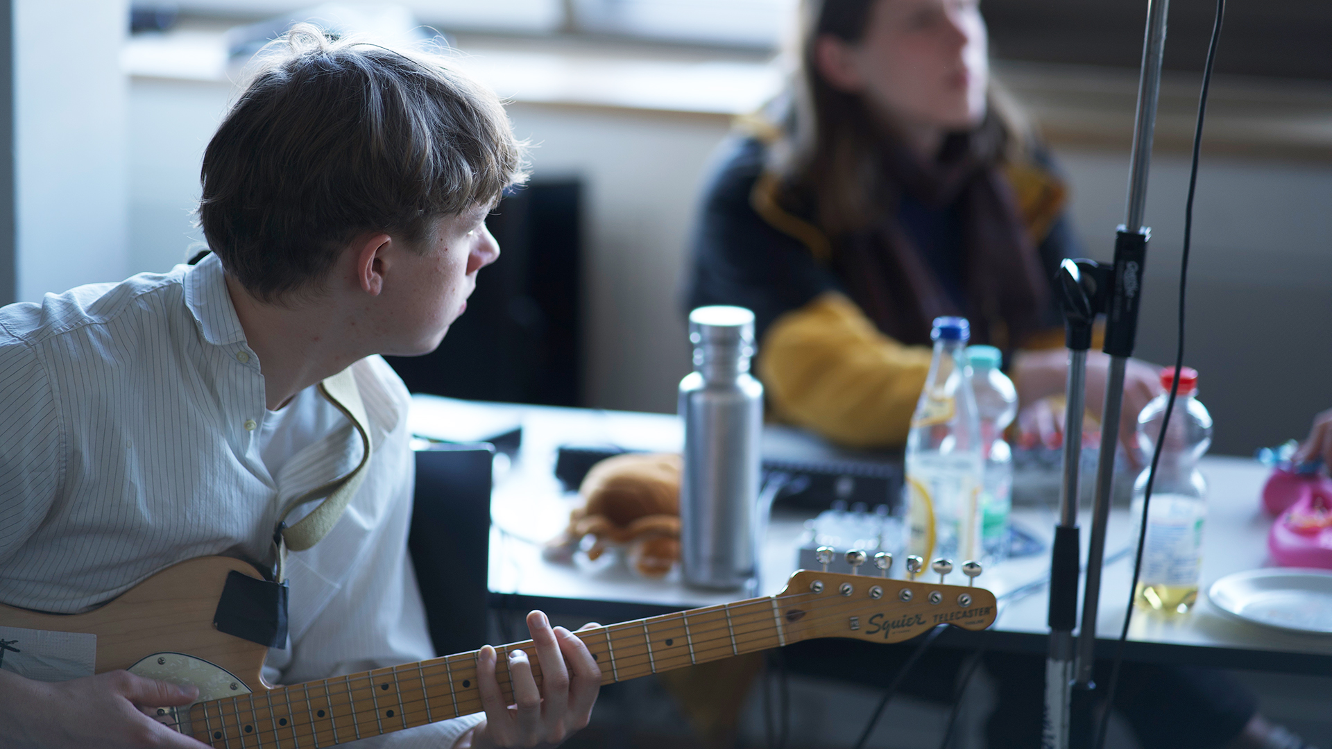 Eine Person sitzt vor einem Tisch und hält eine E-Gitarre